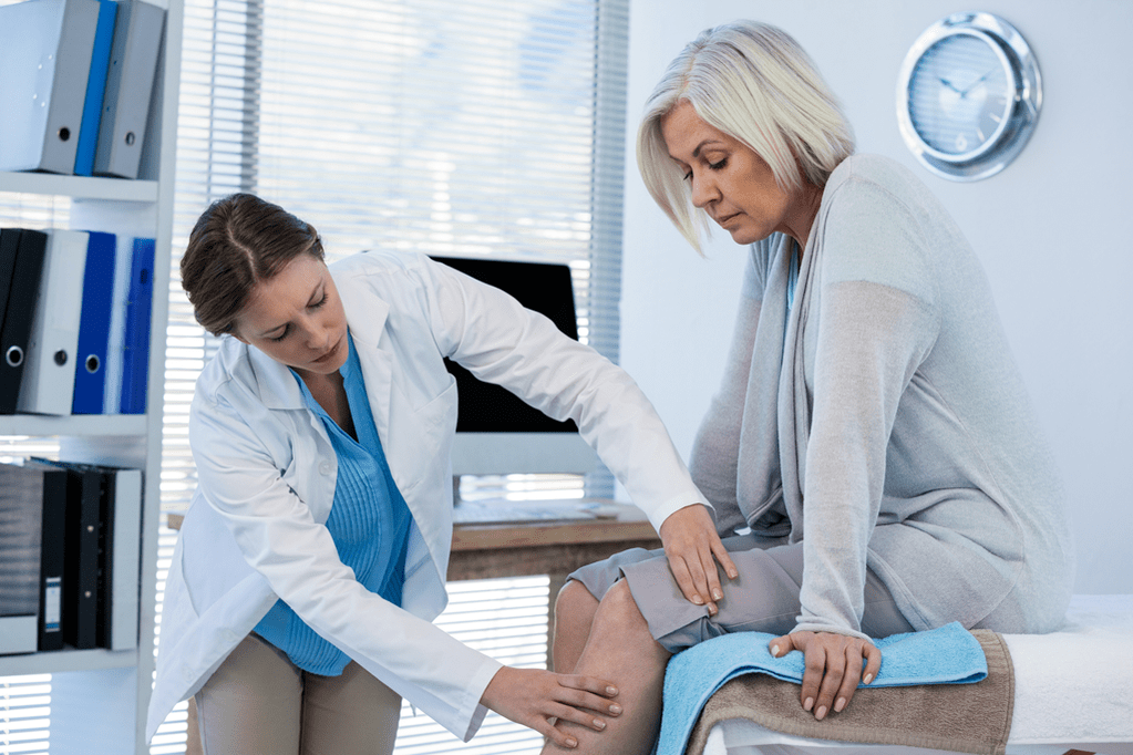 A patient with osteoarthritis who needs therapy being examined by a doctor
